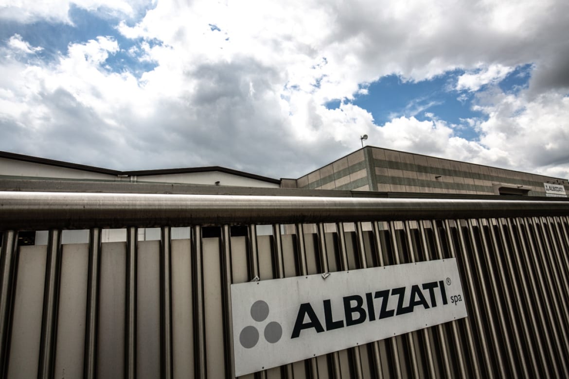 Albizzati sign on the corrugated facade of the plant under a dramatic sky