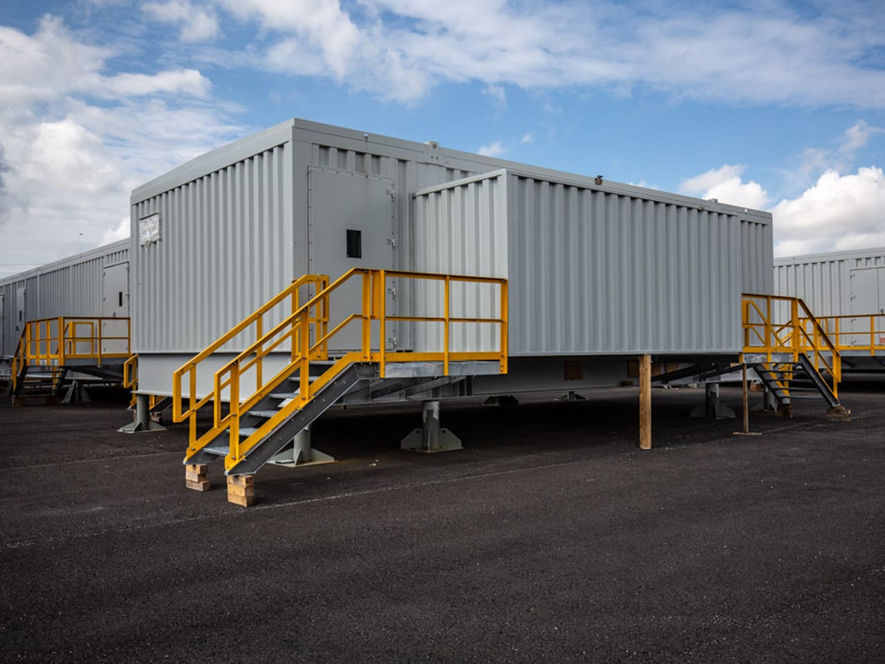 Prefabricated E-house modules with yellow access stairs in the outdoor yard