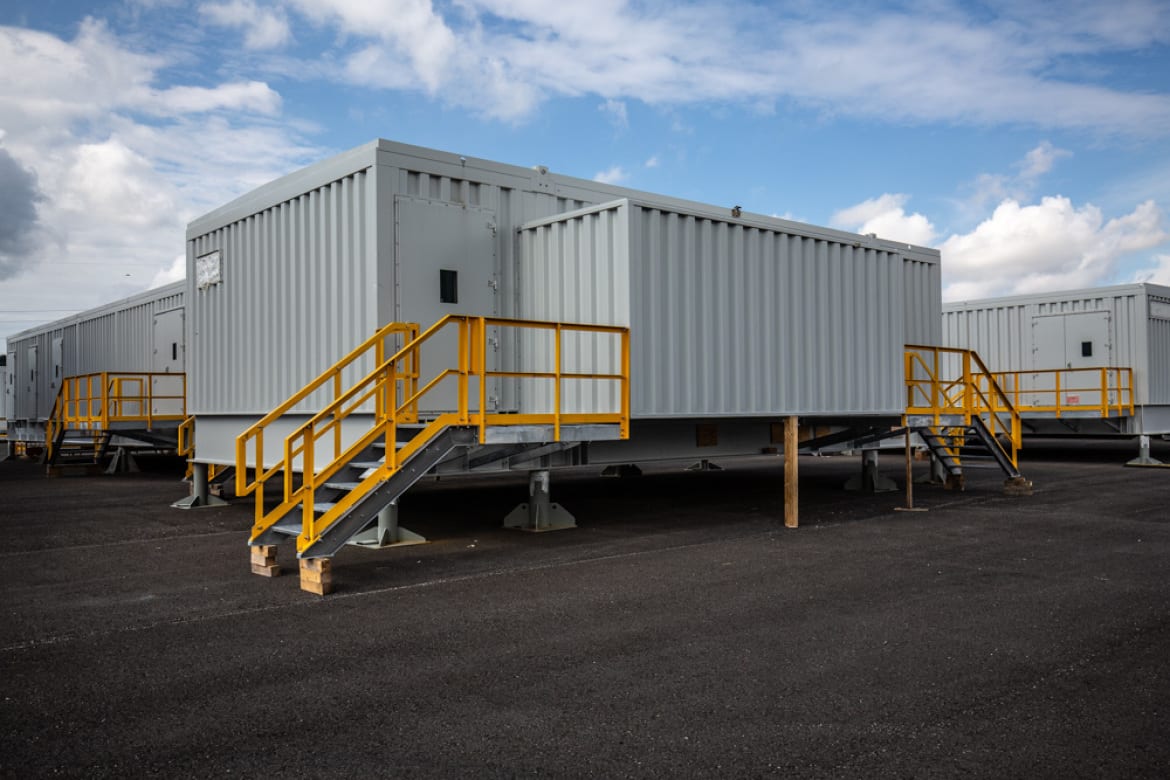 E-house module with external stairway on the yard under a blue sky