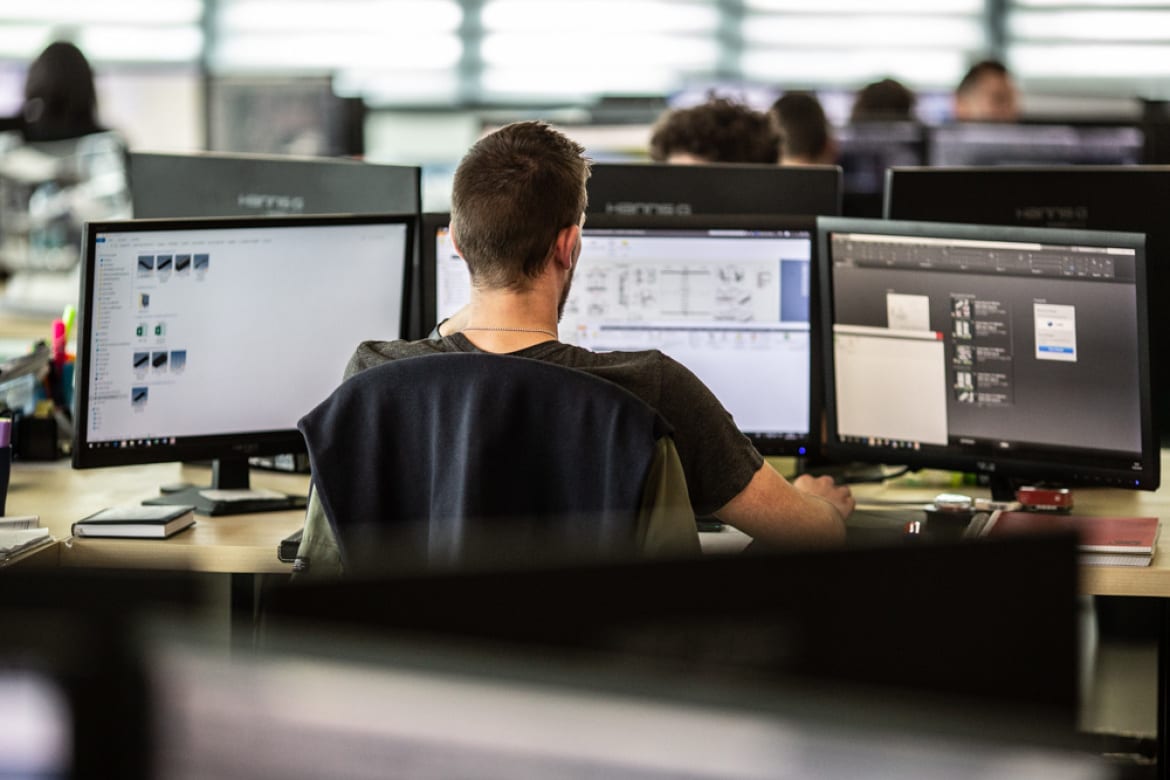 Open-space technical office with engineers at dual-monitor workstations